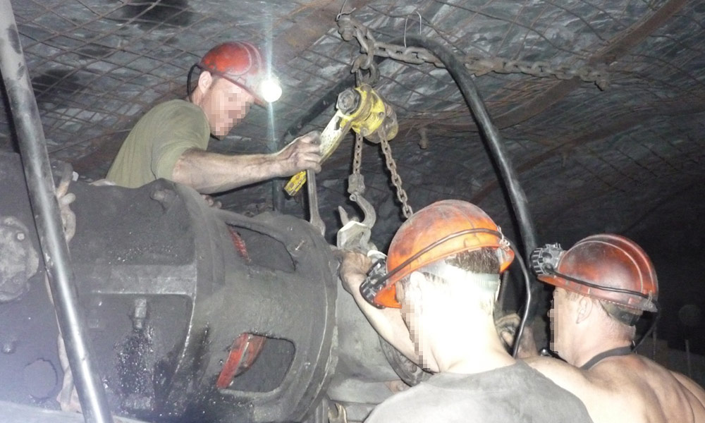 шахтеры в шахте настраивают оборудование